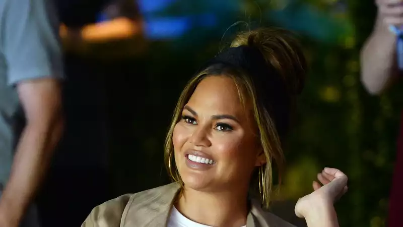 Chrissy Teigen presents leggings with John's face on the hips.